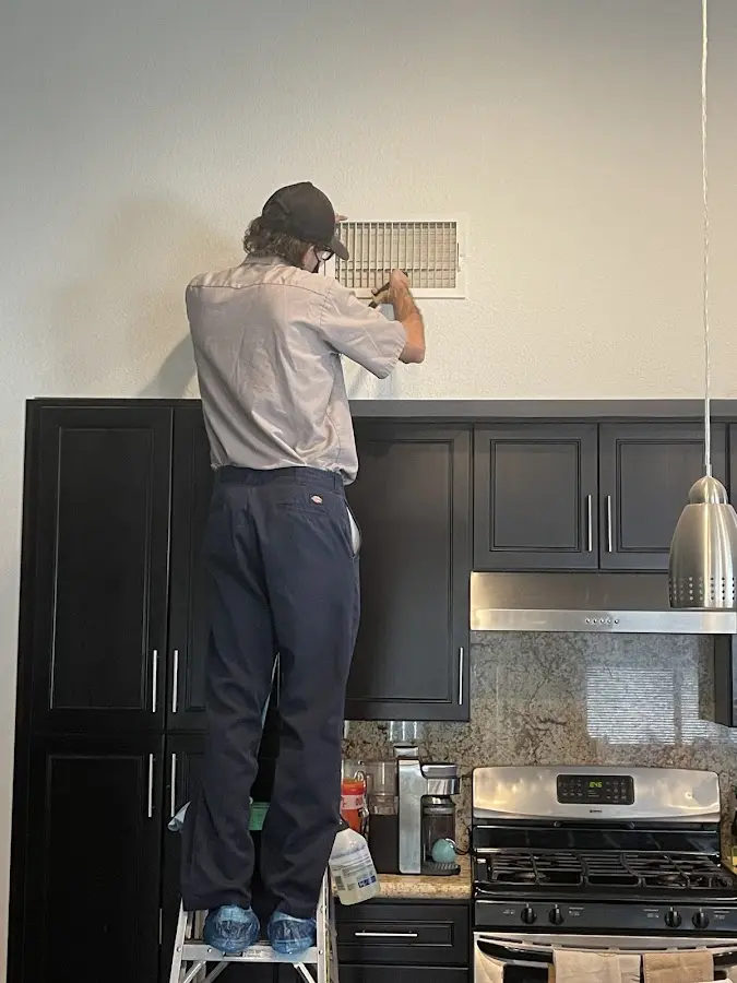 Technician inspecting an air vent during HVAC service in Lanett